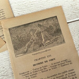 May include: A black and white illustration of a man fishing with a young boy. The illustration is from a book titled "Voyage du jeune Tobie" and is accompanied by text in French. The text includes the chapter title "Chapitre XVI" and the heading "Histoire de Tobie".