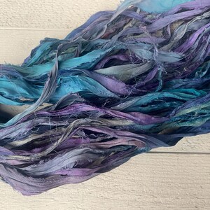 K&ouml;nnte beinhalten: Ein B&uuml;ndel aus t&uuml;rkisfarbenem, blauem und violettem Seidenband. Das Band ist ausgefranst und hat einen rustikalen, handgefertigten Look.