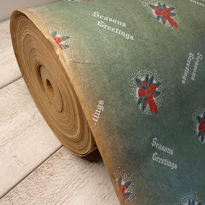 May include: A roll of vintage green wrapping paper with a repeating pattern of red bows and holly sprigs. The paper has a faded, aged look and the text "Seasons Greetings" is printed in white.