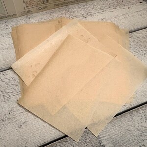 May include: A stack of rectangular sheets of translucent, light tan parchment paper. Each sheet has a smooth, thin texture with subtle variations in colour, giving the paper an aged appearance. The sheets are layered and slightly overlapping.