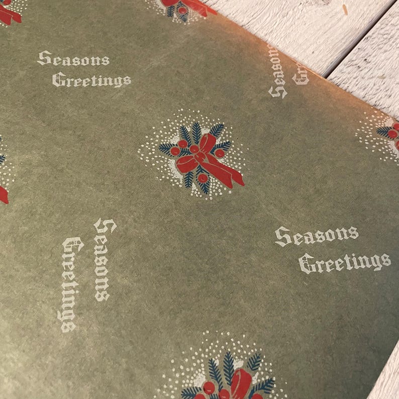 May include: Green wrapping paper with a repeating pattern of red bows and holly sprigs. The paper also has the text "Seasons Greetings" printed in white.