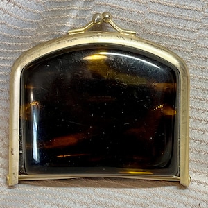 May include: A vintage rectangular coin purse with a tortoiseshell-patterned center and a gold-toned metal frame. The clasp is a small, decorative ball design. The purse is likely from the mid-20th century.