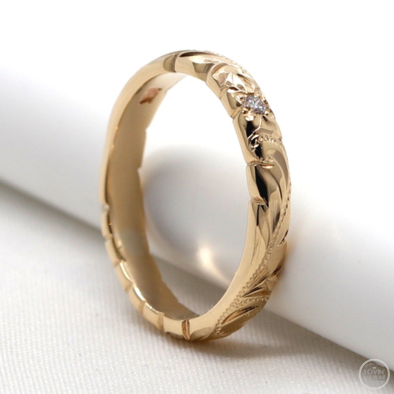 Puede incluir: Una banda de oro con un delicado dise&ntilde;o floral y un peque&ntilde;o acento de diamante. La banda es lisa por dentro y tiene un dise&ntilde;o texturizado y tallado por fuera.