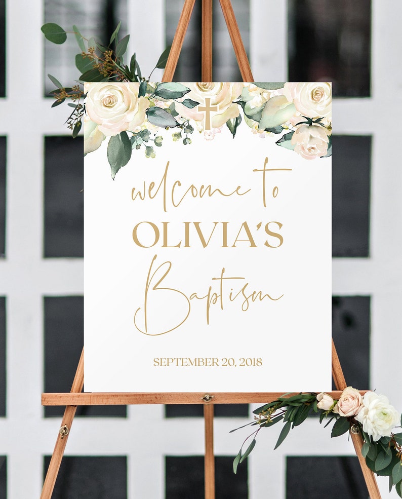 May include: White sign with gold lettering announcing "Welcome to Olivia's Baptism" with a floral border and a gold cross. The date "September 20, 2018" is printed below the text.