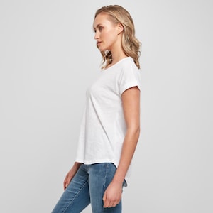 Side profile of model wearing the white scoop neck t shirt highlighting the relaxed silhouette and lightweight cotton fabric.