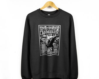 May include: A black sweatshirt featuring a vintage comic book style graphic of Godzilla. The graphic includes the text "The Return of Godzilla" in a white box with a black border. The graphic also features Japanese text and a black and white illustration of Godzilla.