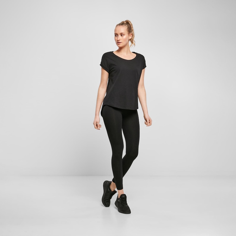 Woman wearing black relaxed fit t shirt with leggings and trainers, casual minimal outfit with loose silhouette and comfortable everyday styling