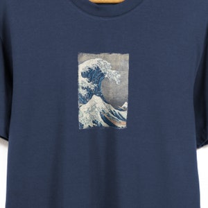 May include: A navy blue t-shirt with a graphic print of the Great Wave off Kanagawa by Katsushika Hokusai.