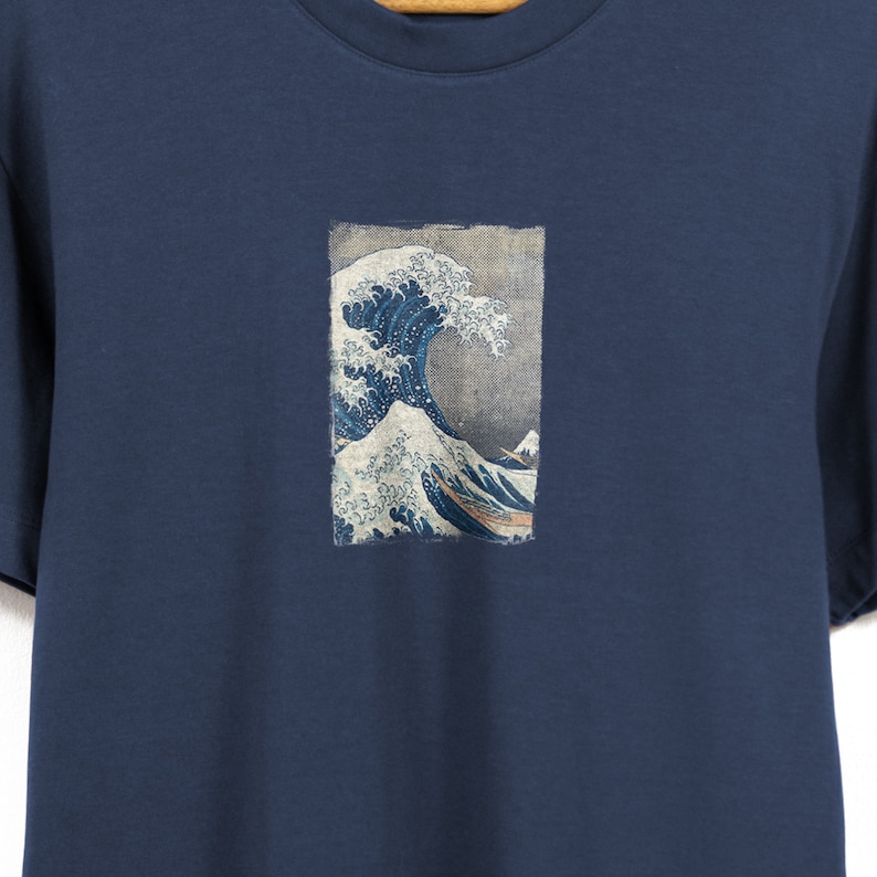 May include: A navy blue t-shirt with a graphic print of the Great Wave off Kanagawa by Katsushika Hokusai.