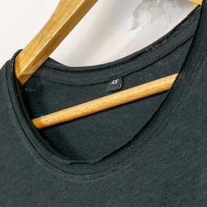 Close-up of scoop neckline on black womens t shirt, soft wide neck with clean stitching and lightweight raw-cut cotton fabric.