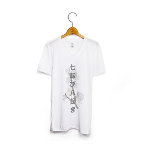 May include: White V-neck t-shirt with a grey floral design and Japanese text that reads "七転び八起き" which translates to "fall down seven times, get up eight".