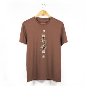 May include: A brown t-shirt with a floral design and Japanese text that reads "七転び八起き" on the front.