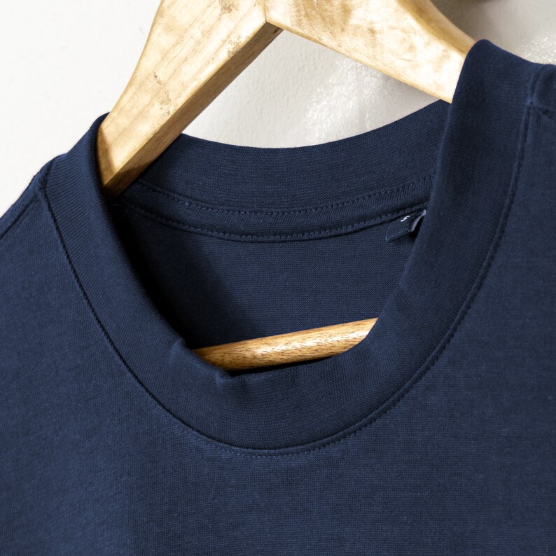 May include: A navy blue t-shirt with a ribbed crew neck collar. The shirt is hanging on a wooden hanger.