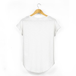 Back view of the white women's scoop neck t shirt showing the relaxed silhouette, rolled sleeves and gently curved hemline.
