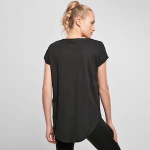 Woman wearing black t shirt from back, relaxed loose fit with longer curved hem and soft drape, minimal plain design for versatile styling