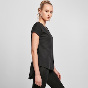 Woman wearing black relaxed fit t shirt side view, showing loose drape and curved hem, paired with leggings for casual everyday outfit