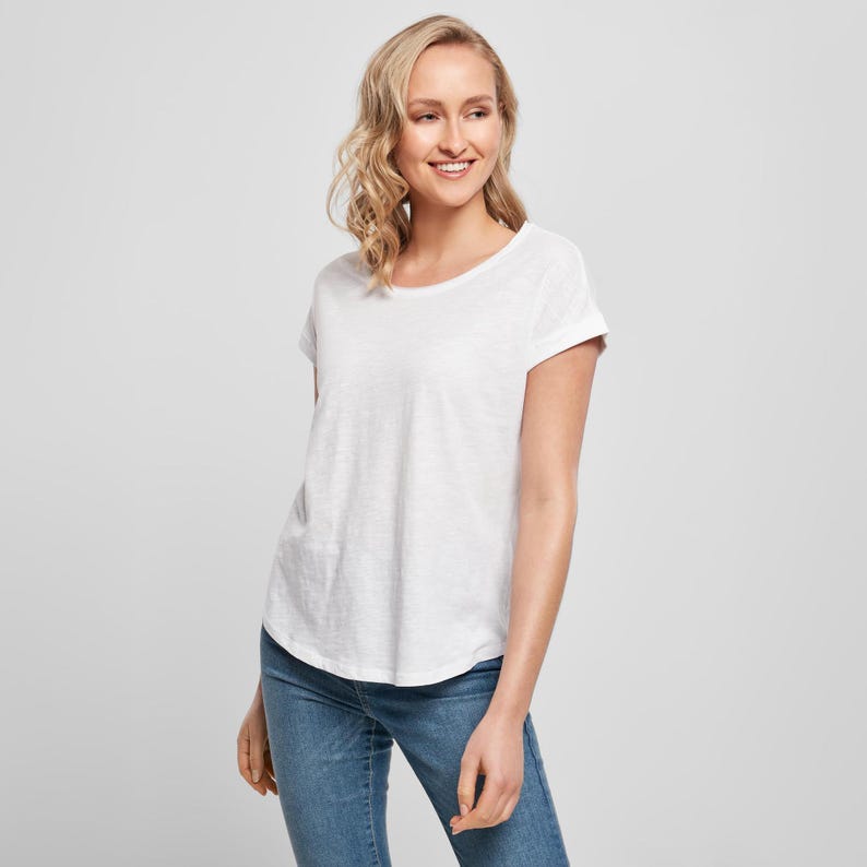 Front model view showing the relaxed fit of the white scoop neck t shirt paired with denim jeans and trainers for a casual everyday look.