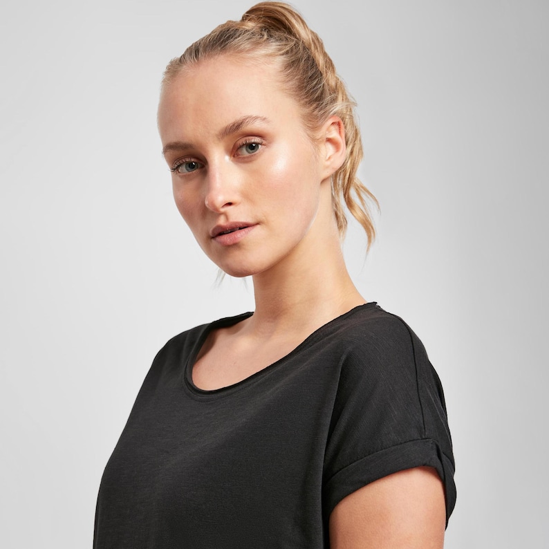 Woman wearing black scoop neck t shirt front view, relaxed fit with soft fabric and clean minimalist style suitable for everyday wear