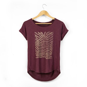 Cherry red relaxed fit women’s t-shirt with rolled sleeves and curved hem, featuring a large central botanical fern print in a soft gold tone, displayed on a hanger against a neutral background.