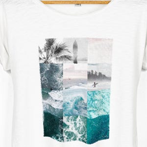 White relaxed fit women's t-shirt with rolled sleeves featuring a coastal collage graphic made from ocean waves, tropical palms, a surfboard silhouette, seaside horizon and surfer photography in muted turquoise, seafoam and soft grey tones.