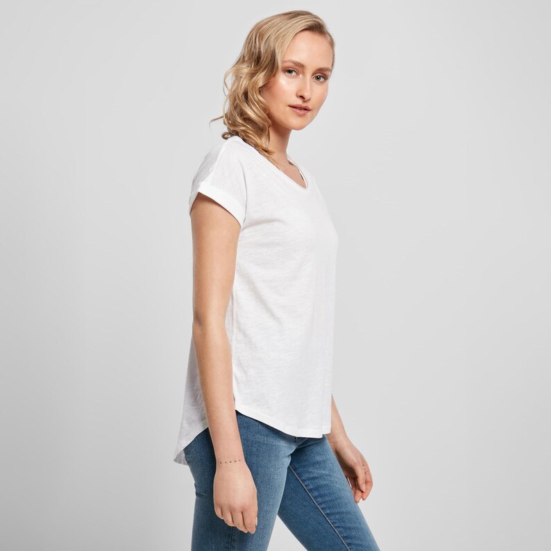 Side view of model wearing the white scoop neck t shirt showing the relaxed drape of the lightweight slub cotton fabric and the softly curved hemline.