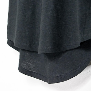 Close-up of curved hem on black womens t shirt, showing layered front and longer back shape with soft drape and lightweight cotton material