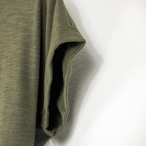 Zoomed view of the rolled sleeve on an olive green women’s scoop neck tee, made from soft slub cotton. The short sleeve is casually cuffed, adding to the laid-back fit and natural feel. This earthy t-shirt is perfect for relaxed styling.