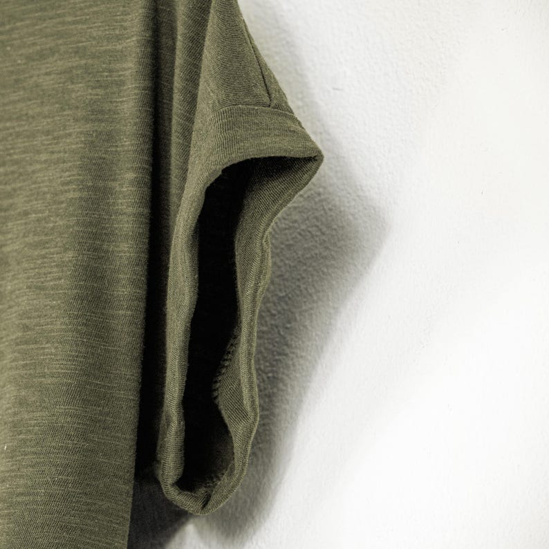 Zoomed view of the rolled sleeve on an olive green women’s scoop neck tee, made from soft slub cotton. The short sleeve is casually cuffed, adding to the laid-back fit and natural feel. This earthy t-shirt is perfect for relaxed styling.