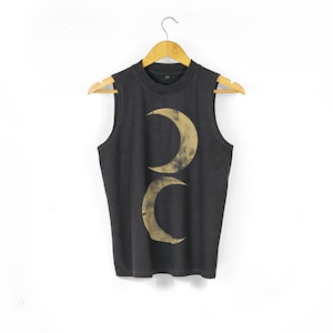 May include: A black sleeveless top featuring a gold-toned graphic of two crescent moons stacked vertically in the centre. The garment has a crew neckline and is displayed on a wooden hanger against a plain white background.