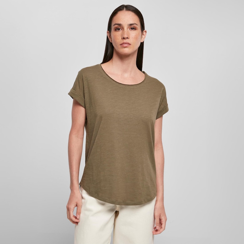 Front-facing model wears olive green women’s t-shirt with scoop neck, short rolled sleeves, and a dropped hem. The shirt is made from lightweight slub cotton, perfect for casual wear.