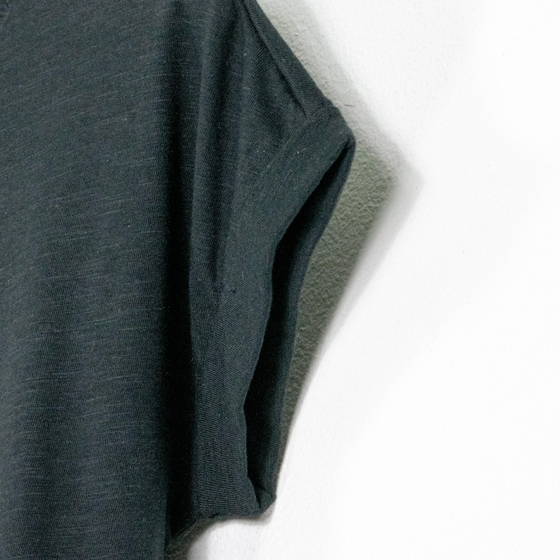 Close-up of rolled sleeve on black t shirt, relaxed fit with soft fabric and casual finish, lightweight cotton with subtle texture