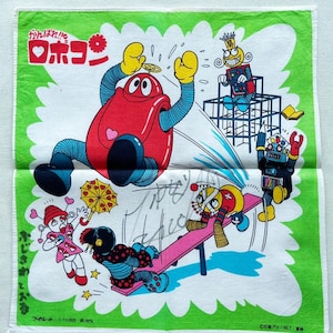 Puede incluir: Un pañuelo de algodón blanco con borde verde presenta una ilustración colorida de personajes de dibujos animados. Los personajes incluyen un robot rojo, una niña con cabello rosado, una niña con cabello negro, un robot con cabeza amarilla y un robot con cabeza azul. El pañuelo tiene el texto japonés "Kawaii wa!" y "ロボン" en la esquina superior izquierda.