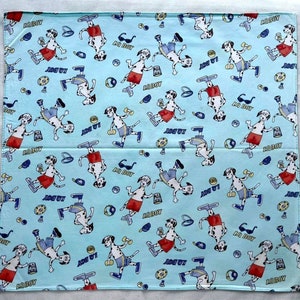 May include: A blue bandana with a repeating pattern of Dalmatian dogs wearing sunglasses and shorts. The dogs are holding various items, including a drink, a dumbbell, and a skateboard. The bandana has the text "LA BOY" printed on it.