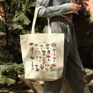 May include: A white canvas tote bag with a colorful illustration of different types of mushrooms. The illustration is titled "Last Map Press presents British Fungi".