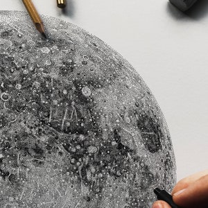 Puede incluir: Un primer plano de un dibujo en blanco y negro de la luna, creado utilizando una t&eacute;cnica de puntillismo. La luna est&aacute; dibujada en detalle, con cr&aacute;teres y otras caracter&iacute;sticas de la superficie visibles.