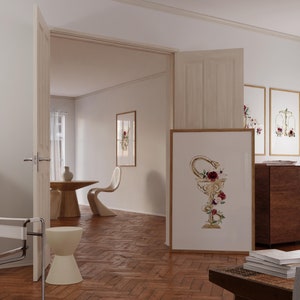 Puede incluir: Una habitaci&oacute;n blanca con suelo de madera, una puerta blanca y una mesa blanca con dos sillas. Hay una impresi&oacute;n enmarcada en la pared con una serpiente dorada y flores en una copa. Hay otras impresiones enmarcadas en la pared con dise&ntilde;os florales.