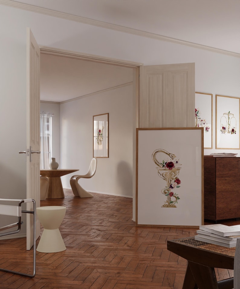 Puede incluir: Una habitaci&oacute;n blanca con suelo de madera, una puerta blanca y una mesa blanca con dos sillas. Hay una impresi&oacute;n enmarcada en la pared con una serpiente dorada y flores en una copa. Hay otras impresiones enmarcadas en la pared con dise&ntilde;os florales.