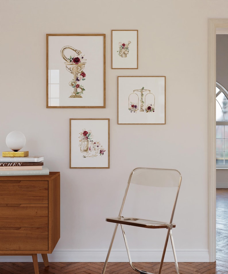 Puede incluir: Cuatro impresiones de acuarela enmarcadas con acentos dorados y dise&ntilde;os florales. Las impresiones presentan una serpiente envuelta alrededor de una copa, una balanza, un frasco con flores y una calavera con flores.