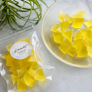 May include: A clear plastic pouch filled with yellow, translucent, geometric crystal jelly candy, featuring a white circular label with the text Kohakuto Crystal Jelly Candy Kohakuto.com by Wagashi Studio, alongside a glass bowl of the same candy.