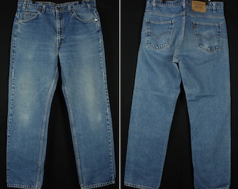 Puede incluir: Vaqueros de mezclilla azul claro, mostrados de frente y de espalda, con un diseño clásico de cinco bolsillos. Los vaqueros tienen un corte de pierna recta y un lavado descolorido, con detalles de costura visibles. Una etiqueta de cuero marrón es visible en la parte trasera.