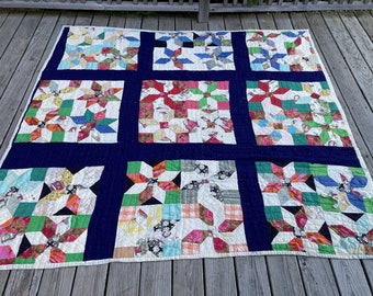 Könnte beinhalten: Eine Patchwork-Decke mit dunkelblauem Hintergrund und neun Quadraten, die ein Sternenmuster in verschiedenen Farben wie Rot, Grün, Blau und Weiß zeigen.