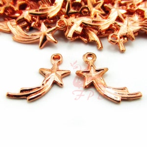 Op de afbeelding: Een stapel roze gouden vallende ster bedels met een vijfpuntige ster aan het einde van elke bedel. De bedels hebben een lus aan de bovenkant om aan sieraden te bevestigen.
