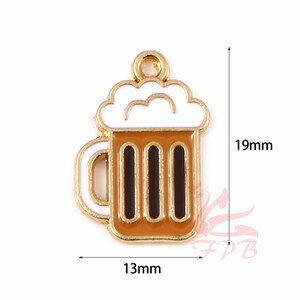 May include: Gold-tone metal charm shaped like a beer mug with white foam on top. The mug is filled with a brown liquid and has three vertical black lines. The charm is 1.9 cm tall and 1.3 cm wide.
