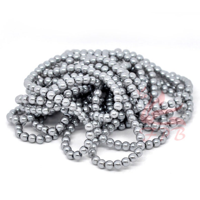 May include: A strand of silver-colored round glass beads. The beads are small and have a smooth, shiny finish.