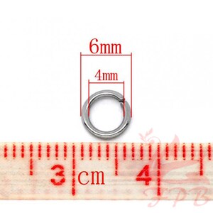May include: A silver jump ring measuring 6mm in diameter and 4mm in width. The ring is shown next to a ruler.