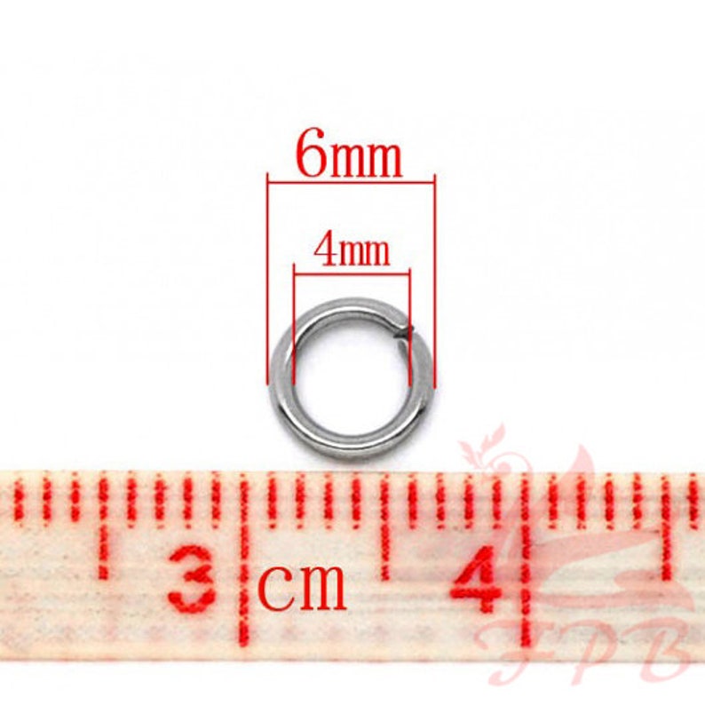 May include: A silver jump ring measuring 6mm in diameter and 4mm in width. The ring is shown next to a ruler.