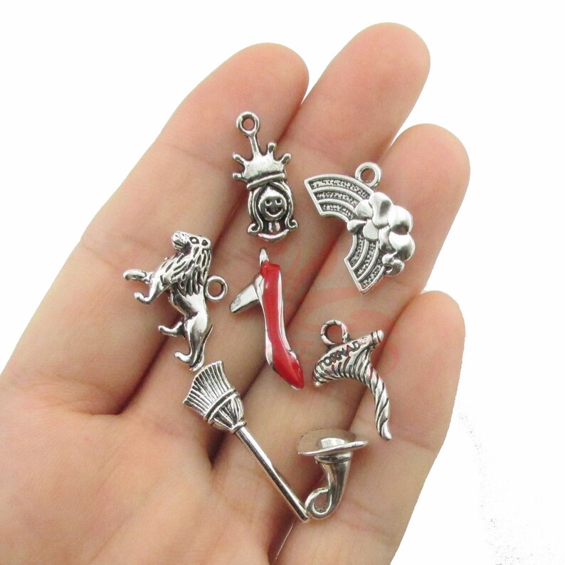 Puede incluir: Una colecci&oacute;n de dijes plateados, que incluyen un le&oacute;n, una corona, un arco&iacute;ris, un zapato rojo, una escoba y un dije en forma de cuerno. Los dijes son peque&ntilde;os y detallados, perfectos para la creaci&oacute;n de joyas o proyectos de manualidades.