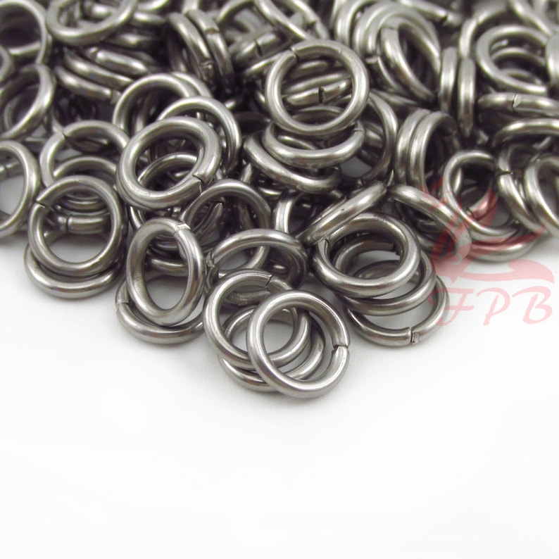 May include: A pile of silver jump rings, a type of metal ring used in jewelry making.