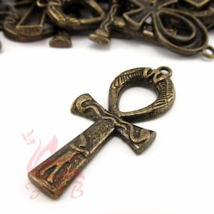 May include: A gold-toned metal Ankh pendant with intricate details. The pendant is a popular symbol of ancient Egyptian culture and is often used in jewelry and other decorative items.