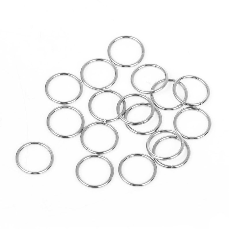 May include: A pile of silver jump rings, a type of metal ring used in jewelry making.